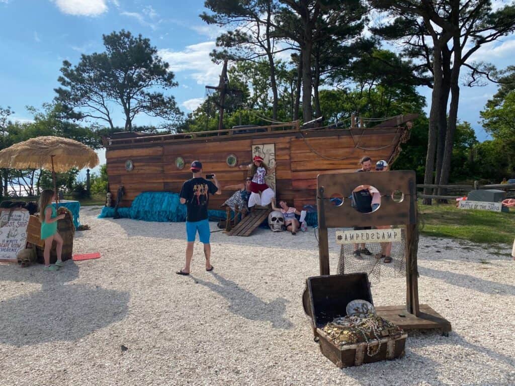 A group of people standing in front of a pirate ship at Chesapeake Bay KOA, excitedly preparing for their upcoming Pirate Ship Escape Room adventure.