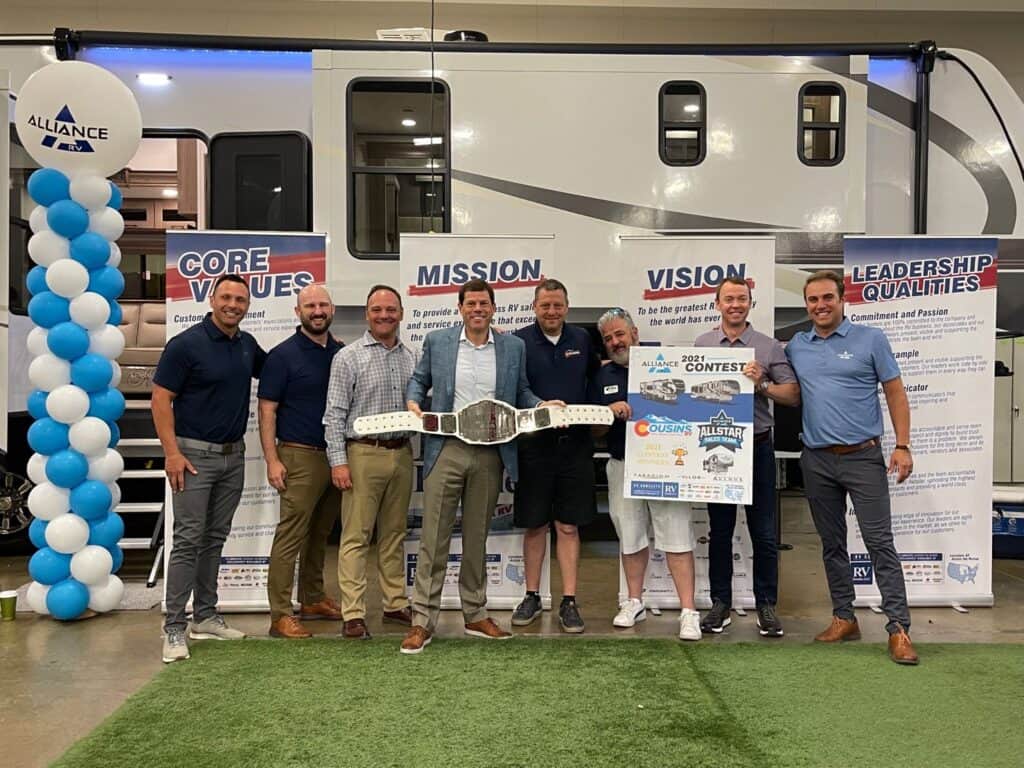 A group of people posing in front of an Alliance RV.