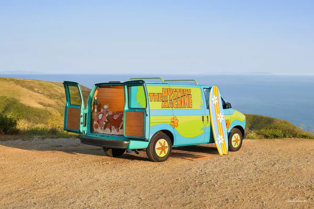 Mystery Machine van with Scooby-Doo parked on a dirt road.