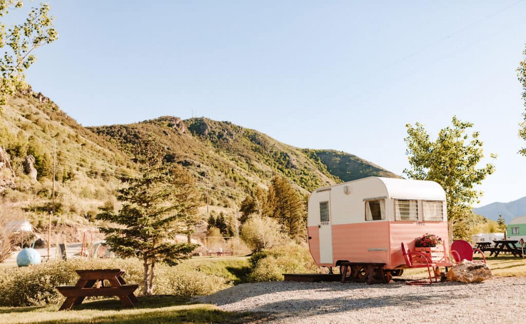 A pink camper sits on a picnic table in the Idaho Campground surrounded by majestic mountains.