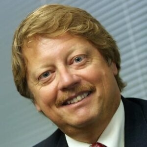 A man in a suit and tie, who happens to be one of the RV Industry Executives, smiles for the camera.