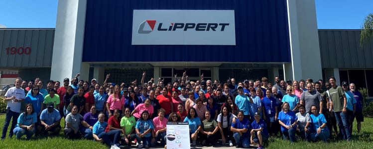 A group of people posing in front of a building to celebrate winning the Top Manufacturing Award in Florida.