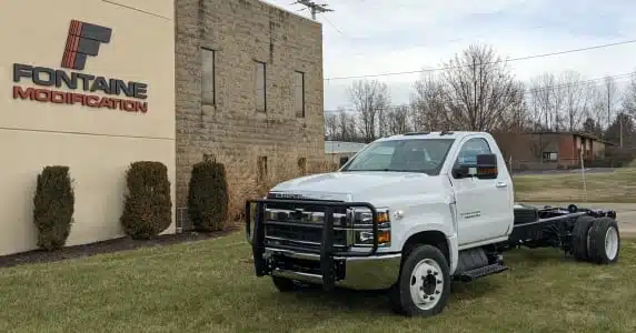 A white Chevrolet DRW parked in front of a Lippert building.