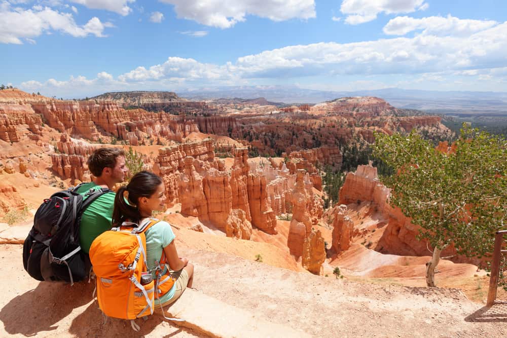 Two people sitting on a cliff overlooking Bryce Canyon, a renowned U.S. National Park.