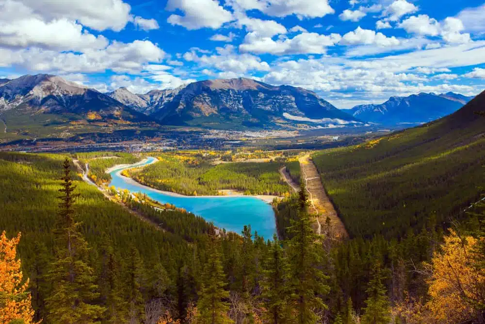 A scenic view of a lake and mountains in the fall, surrounded by Lingering Snowpack in the Kananaskis.