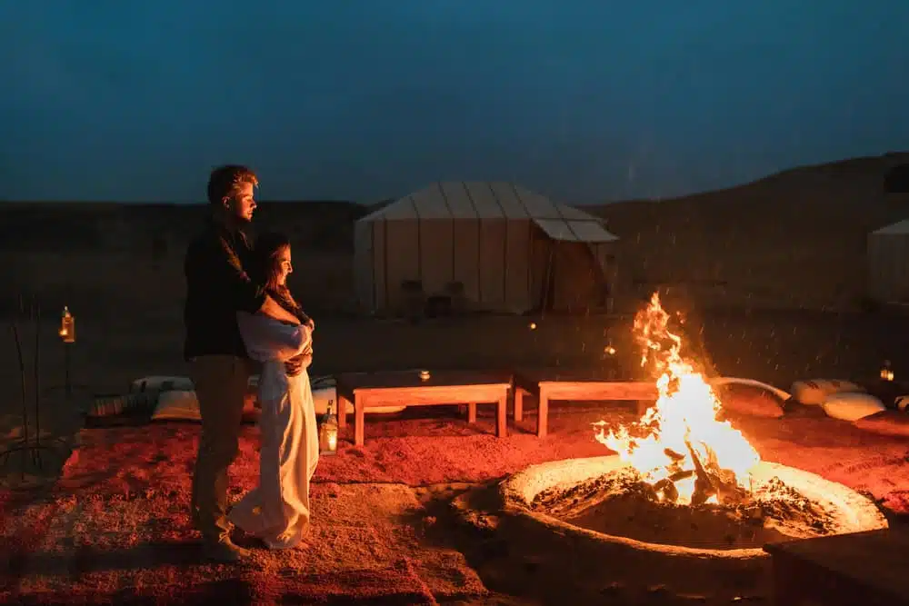 A couple standing in front of a campfire at Ullswater Holiday Park, the UK's best glamping site.