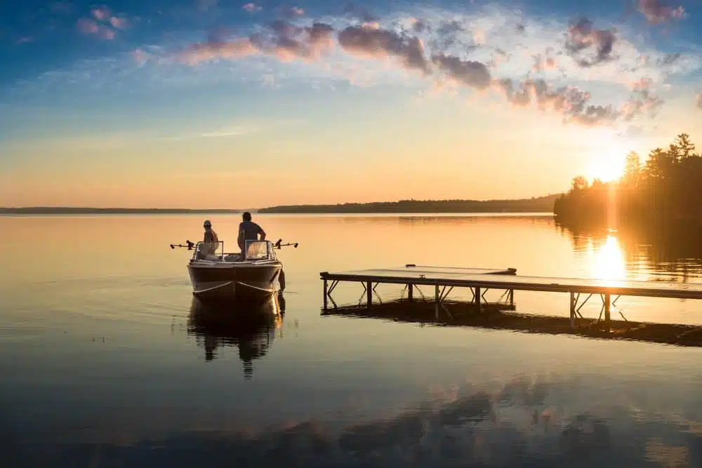 Two people standing on a dock on a lake at sunset in a provincial park.