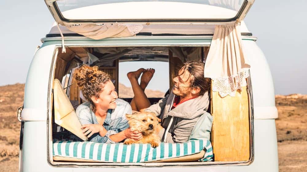 Una pareja con su perro disfruta de un cómodo paseo en una autocaravana compacta alquilada por Road Bear RV.