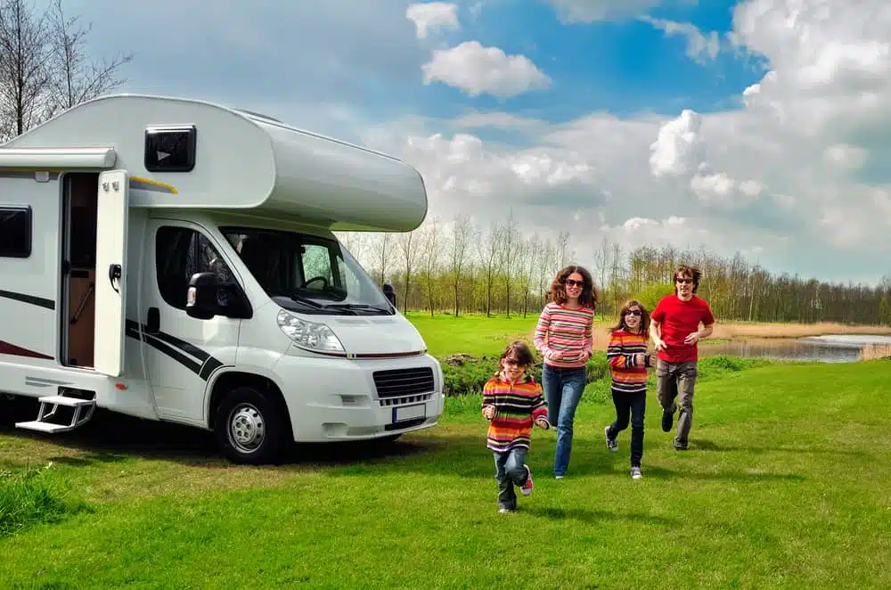 A family enjoying the Camping Industry with their RV in front of a lake.