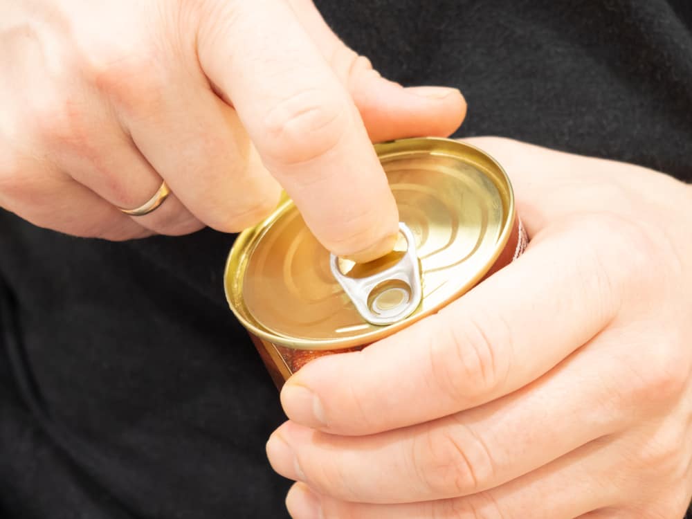 A Chunky can of food is being held by a person's hand during camping at KOA.