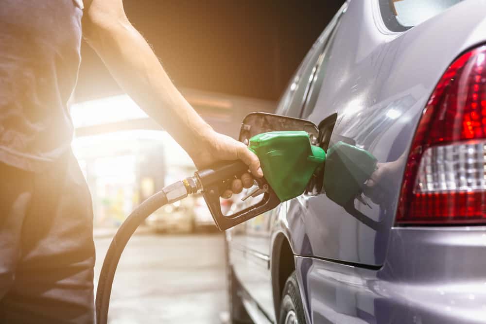 A man filling up his car with gas, potentially for RV travel's growing popularity or to earn up to $500 towards a road trip adventure, and covering 1,000 miles of fuel