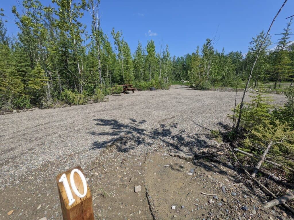 A rustic dirt road with a number on it in the middle of a forest, leading towards the Dinosaur Lake ATV Campground.