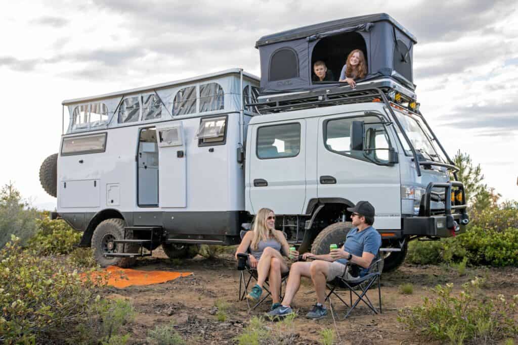 A group of people camping on top of a camper truck.