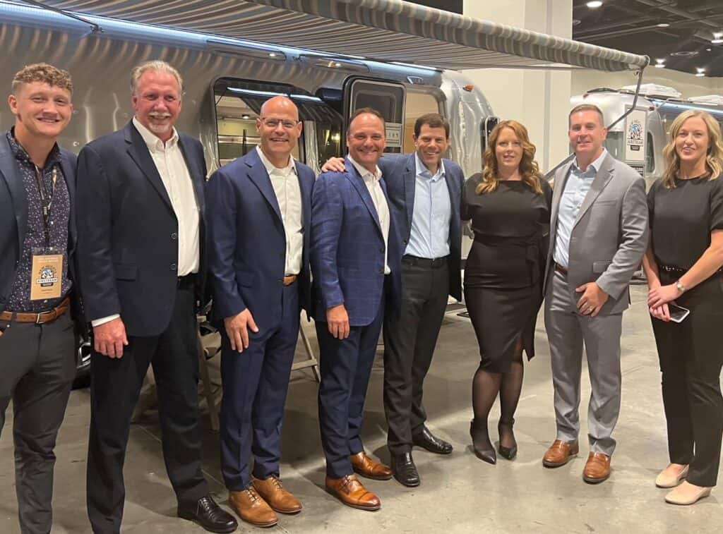 A group of people standing in front of an Airstream trailer dealership.