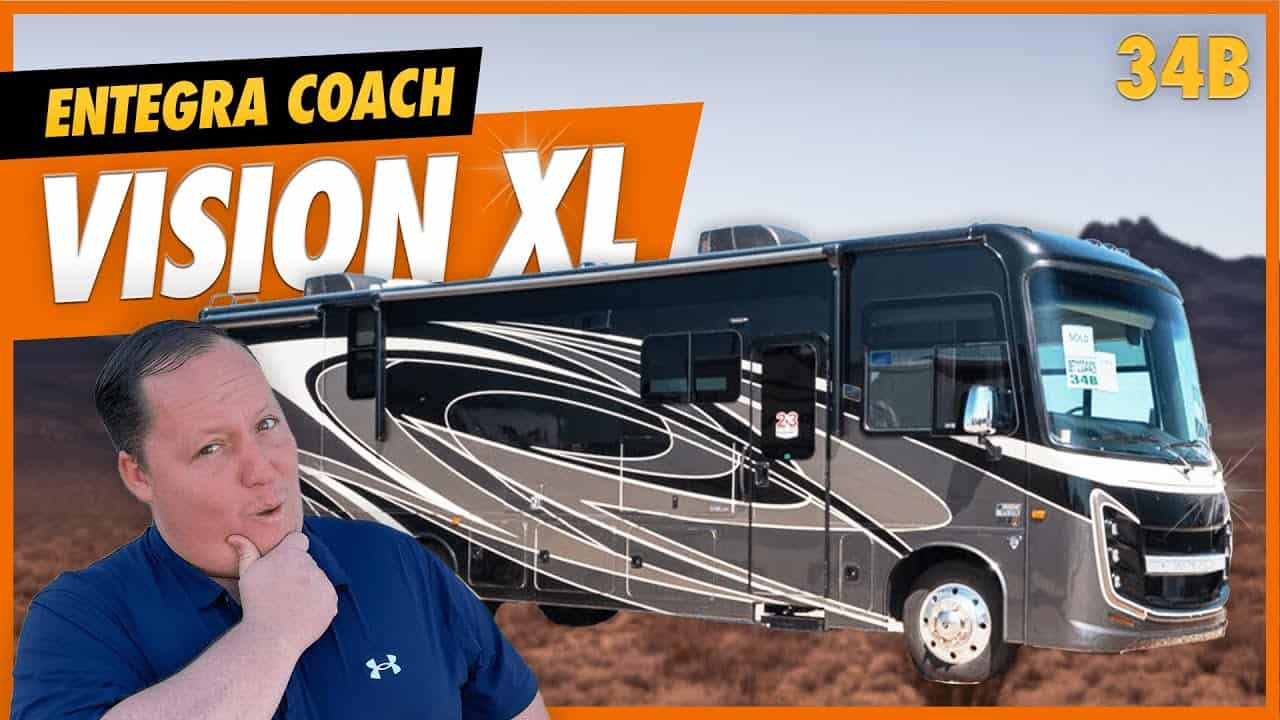 A man is standing in front of a Class A Motorhome with the words Vision XL prominently displayed on the 2022 Entegra Coach.