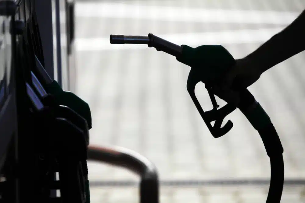 A person is filling up a gas nozzle at a gas station amidst increased gas prices.