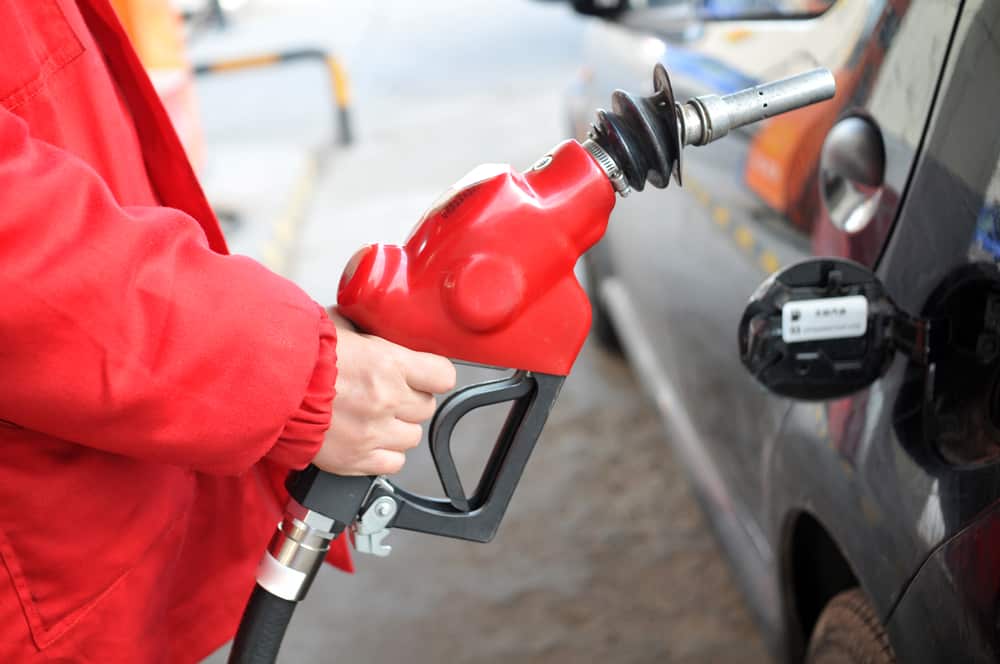 A man is filling up his car with gas as he observes the falling gas prices.