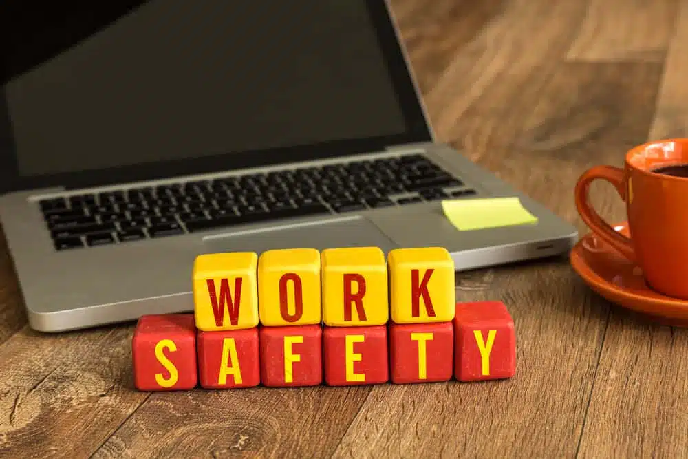 A cup of coffee next to a laptop with the word work safety written on it, highlighting the importance of legal liability and the need to prepare for active shooter events.