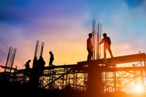 Silhouettes of construction workers on a construction site during sunset.