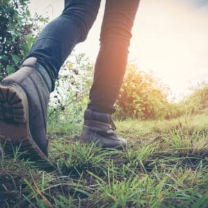 A person walking on a trail in a pair of hiking boots, braving severe rainfall.