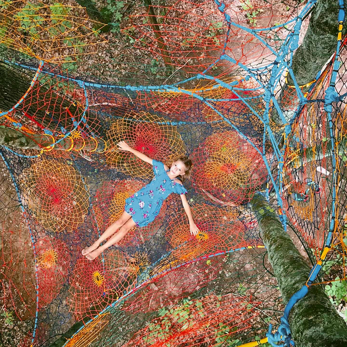 A girl is floating in a net in the Juniper Moon Grove.