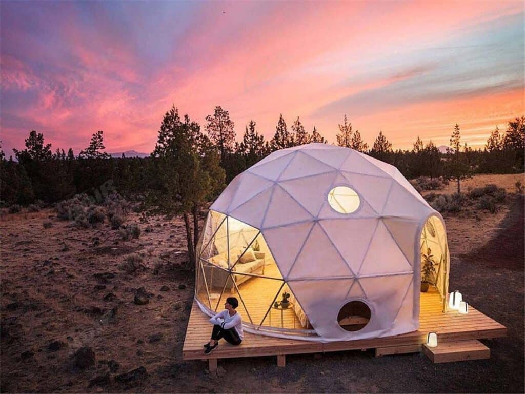 A white dome tent sits on top of a hill in the desert.