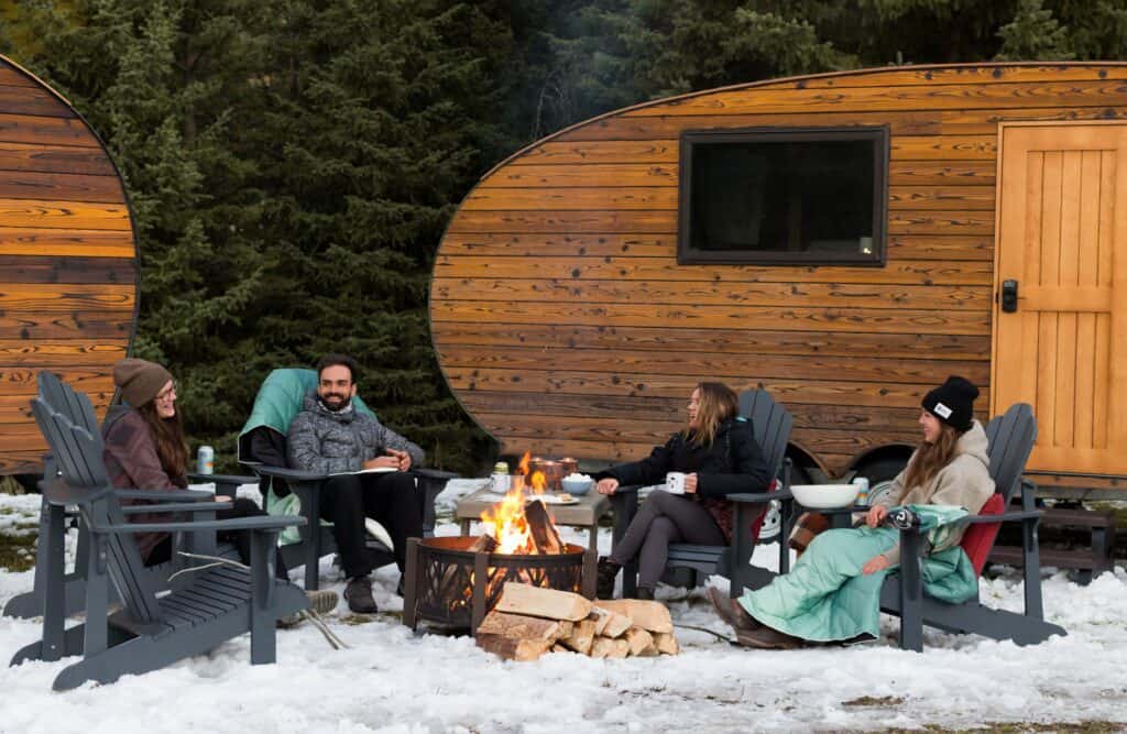 A group of people sitting around a fire in a small cabin during an Adventure Camp.