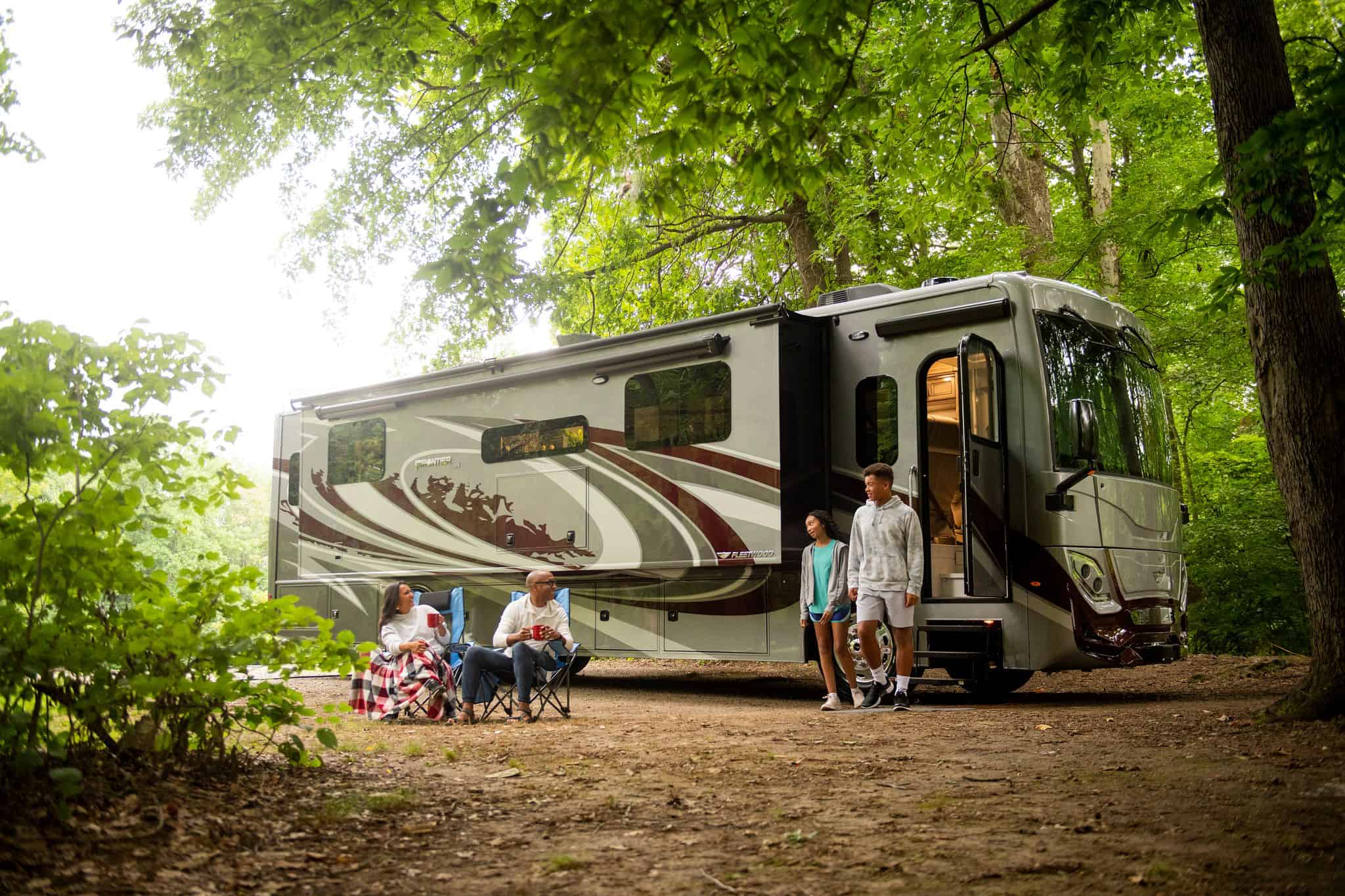 A large Fleetwood RV parked in a wooded area.