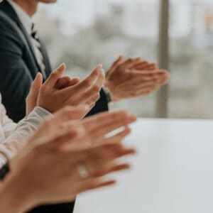 A group of business people clapping at a Fastest-Growing meeting.
