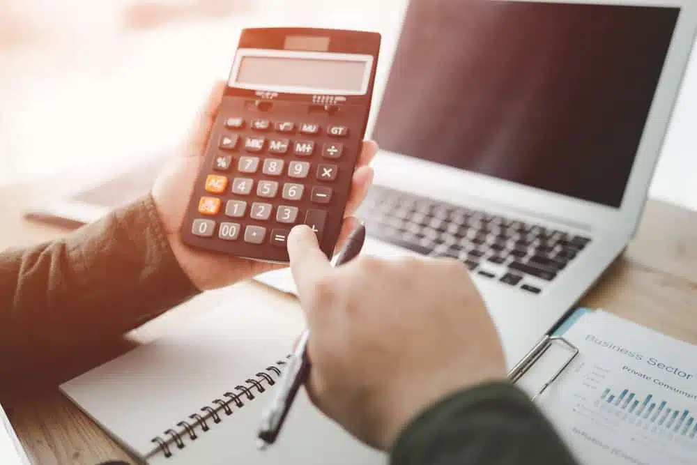 A person using a calculator on a desk.