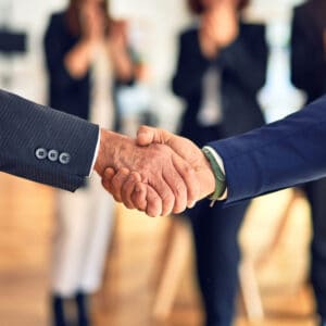 Two business people shaking hands in front of a group of Camper City employees.