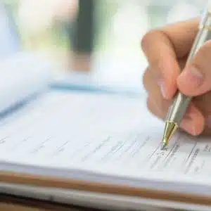 A person writing applications on a paper with a pen.