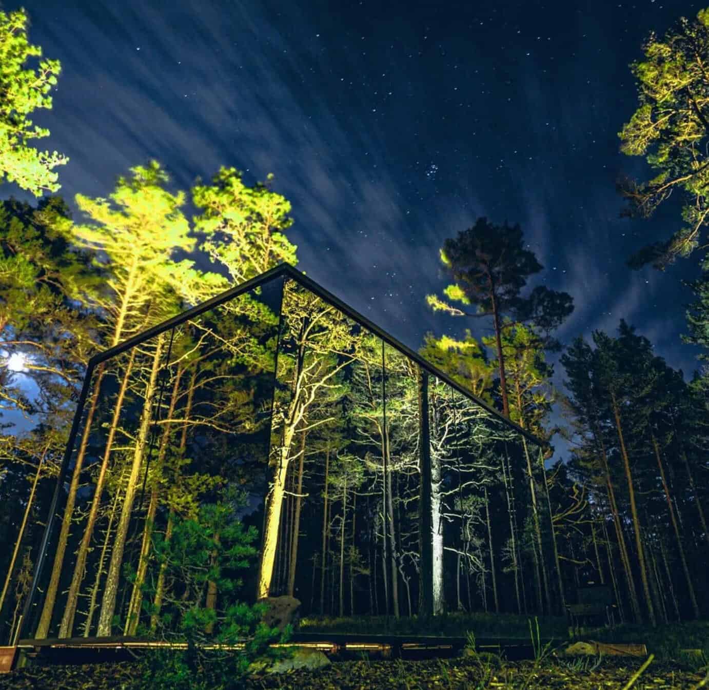 A Mirror Cabin nestled in the Tennessee forest, glistening under the starry night sky, providing a unique glamping experience.