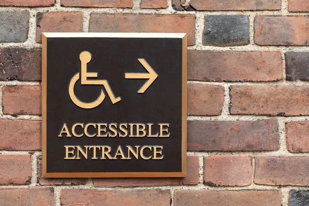 An accessible entrance sign on a brick wall, indicating the level of accessibility for BCLCA member campgrounds.