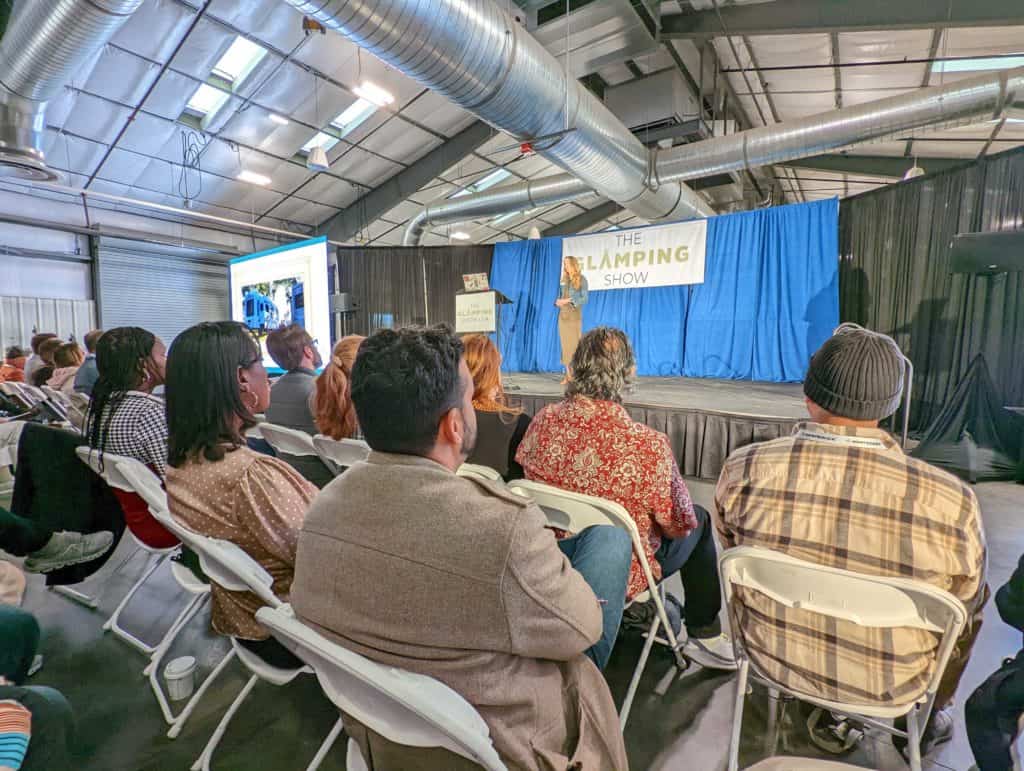 A group of people sitting in chairs watching a Keynote Presentation at The Glamping Show USA 2022, featuring Whitney Scott.