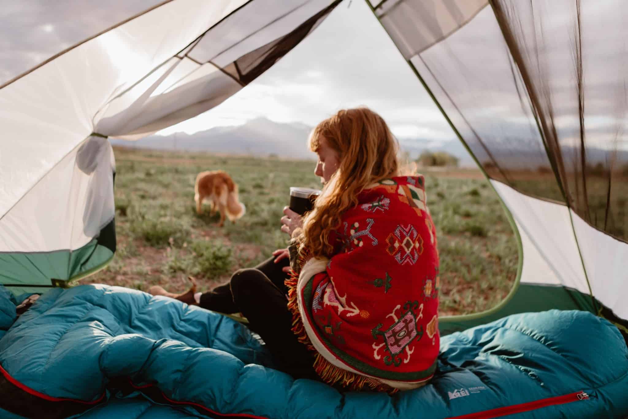 A woman enjoying her cup of coffee while sitting in a tent on private land in Chaffee County, Colorado.