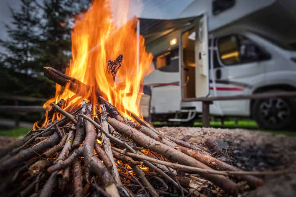 A campfire in front of an RV, showcasing fire prevention tips from National Indoor RV Centers.