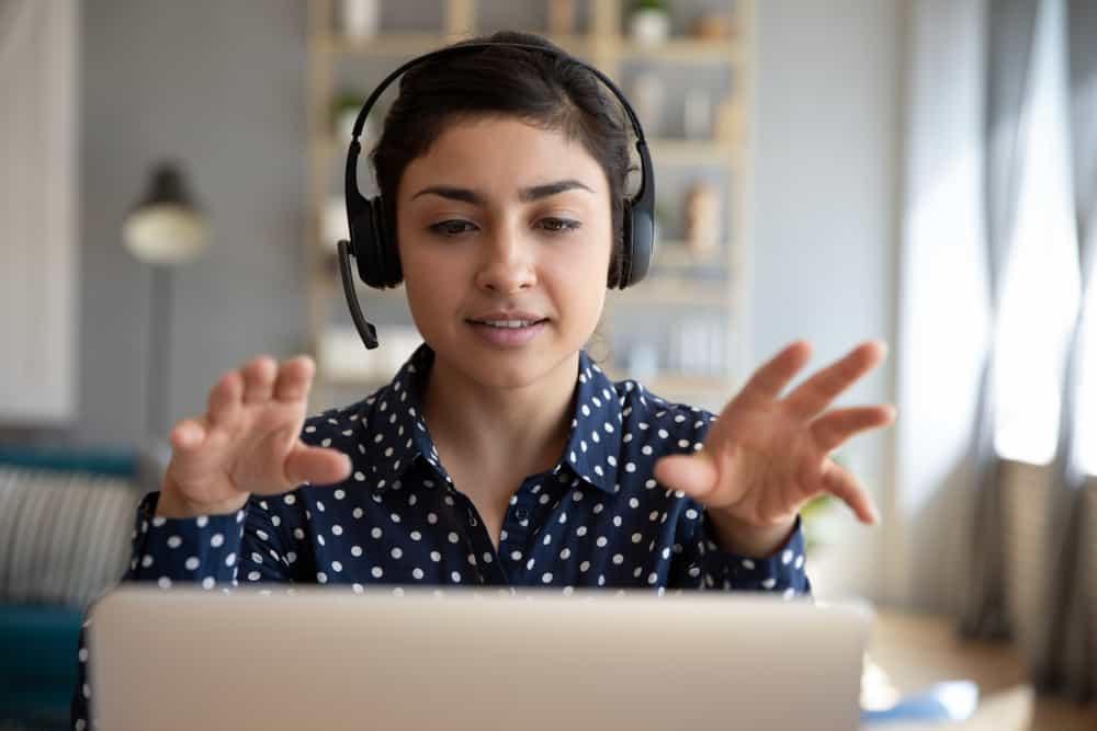 A woman wearing a headset while working on a laptop, possibly engaged in a webinar.