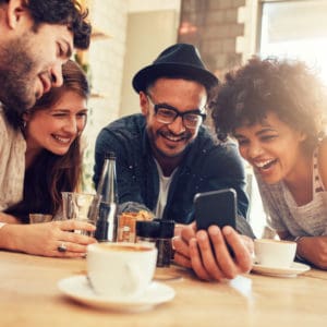 A group of friends sitting around a table using the Lippert online 3D Awning Builder on their cell phone.