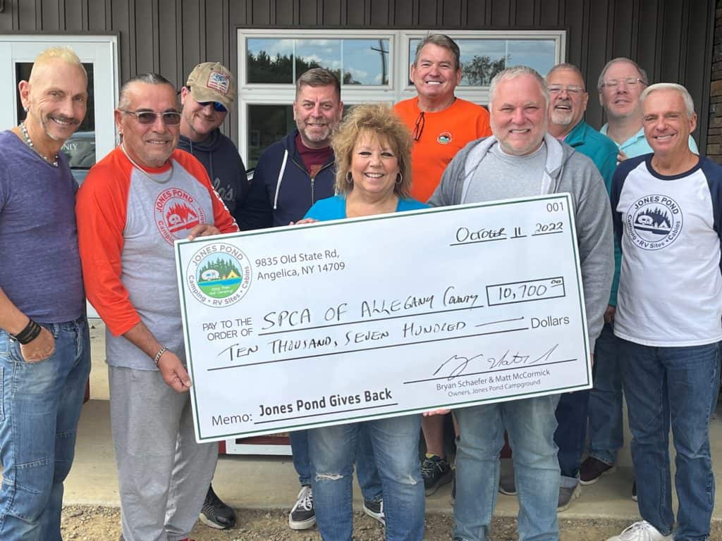 A group of people holding a check in front of a local SPCA building.