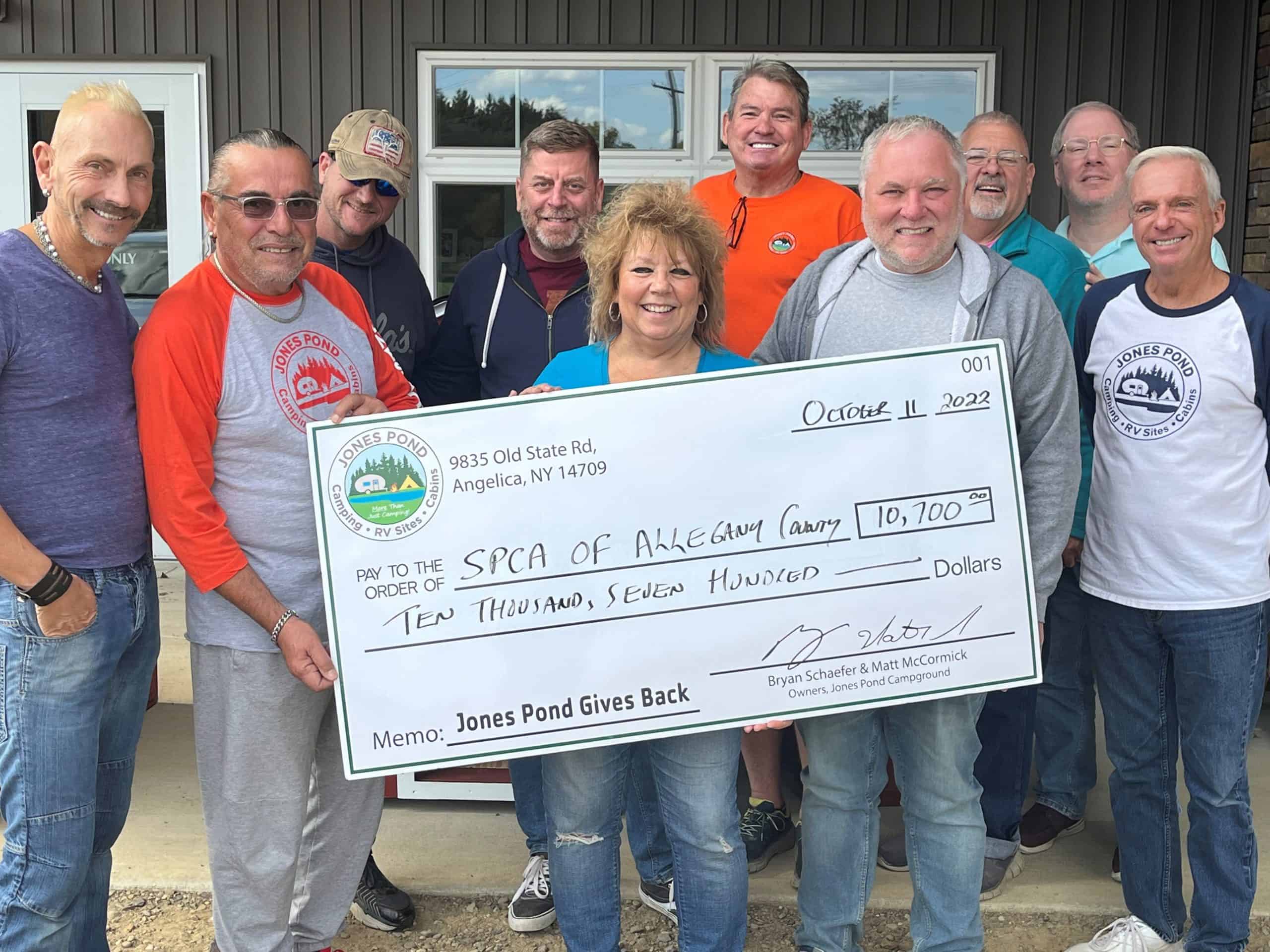 A group of people holding a check in front of a local SPCA building.
