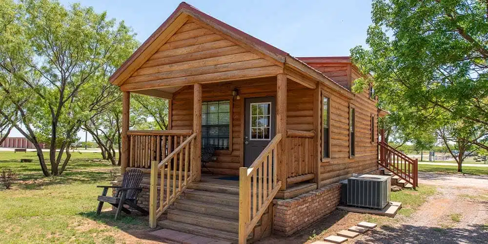 A small cabin in the woods with a porch, located in Wichita Falls, near Jellystone Park.