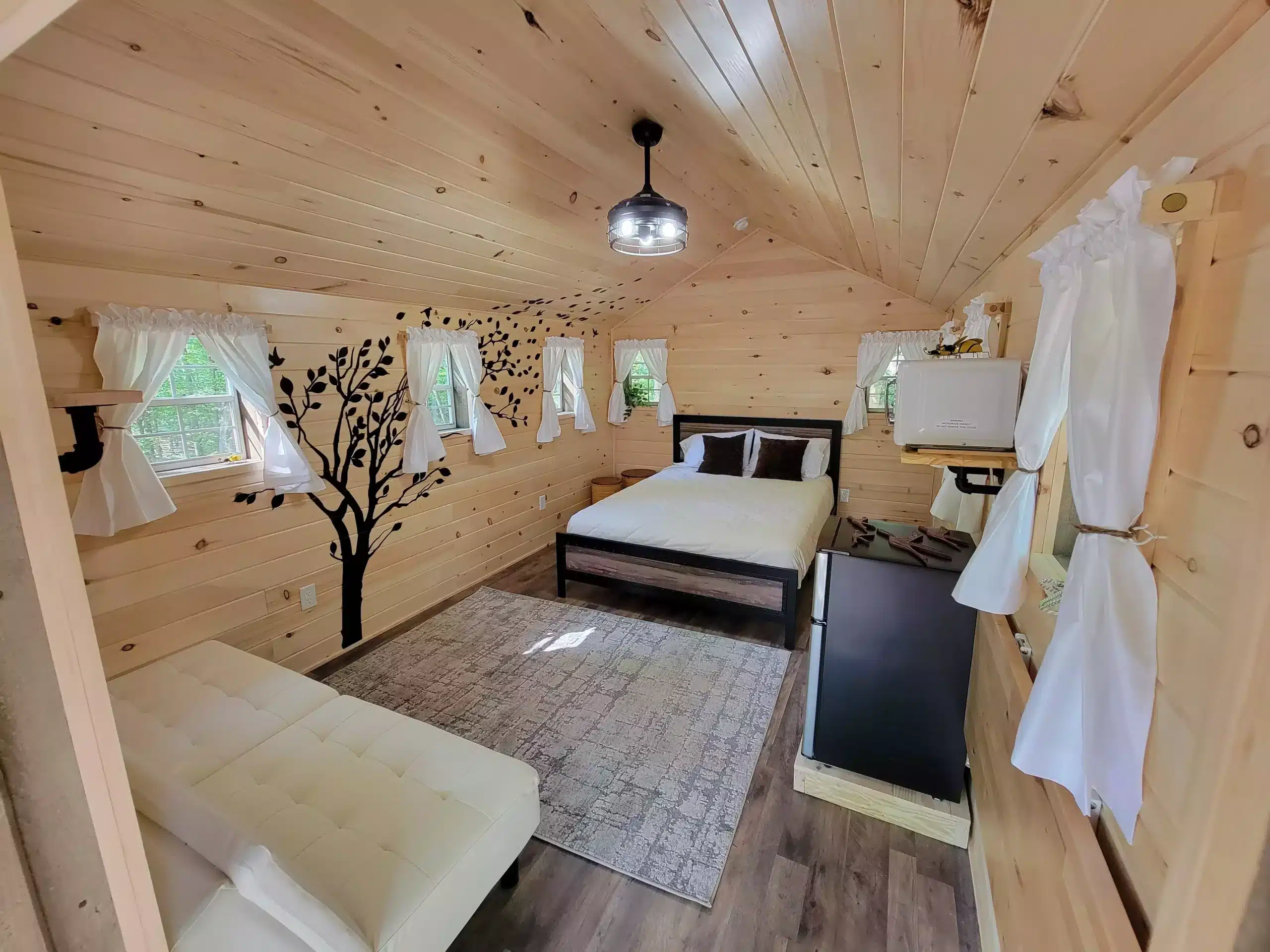 The inside of a tiny house with a bed and a bedside table.