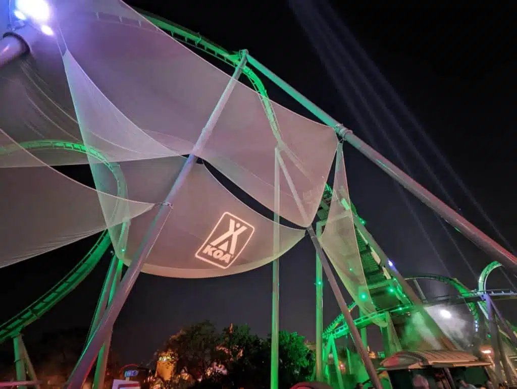 An Exclusive Convention roller coaster at Universal Orlando is lit up at night with green lights.