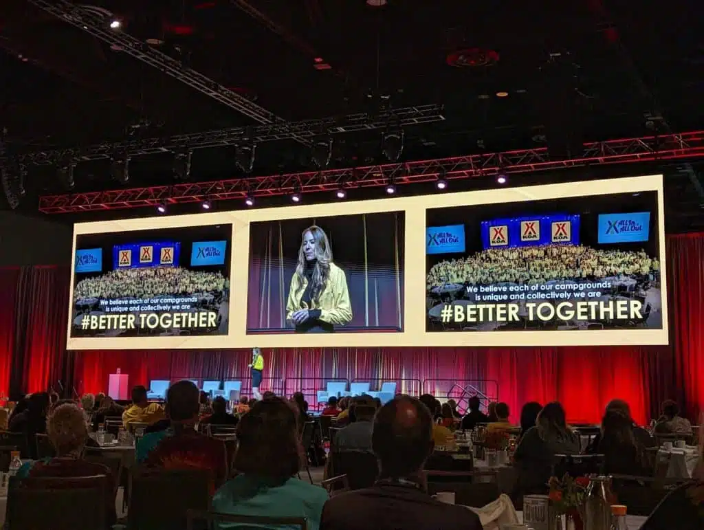 A group of people sitting at a table in front of a large screen, discussing growth mindset in the competitive outdoor hospitality industry.