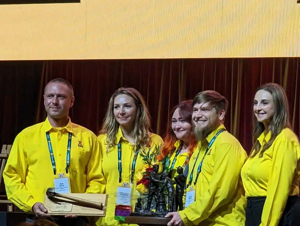 A group of people in yellow shirts posing for a picture at an Awards Celebration.