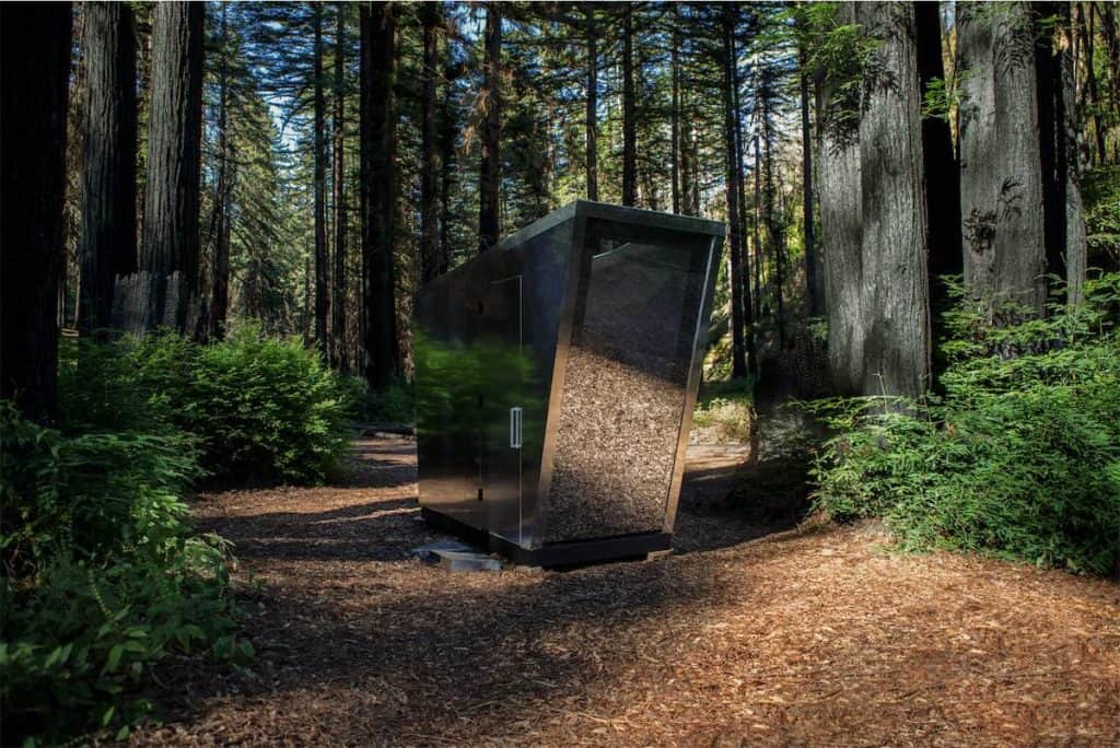 A luxury portable toilet sits in the middle of a forest.