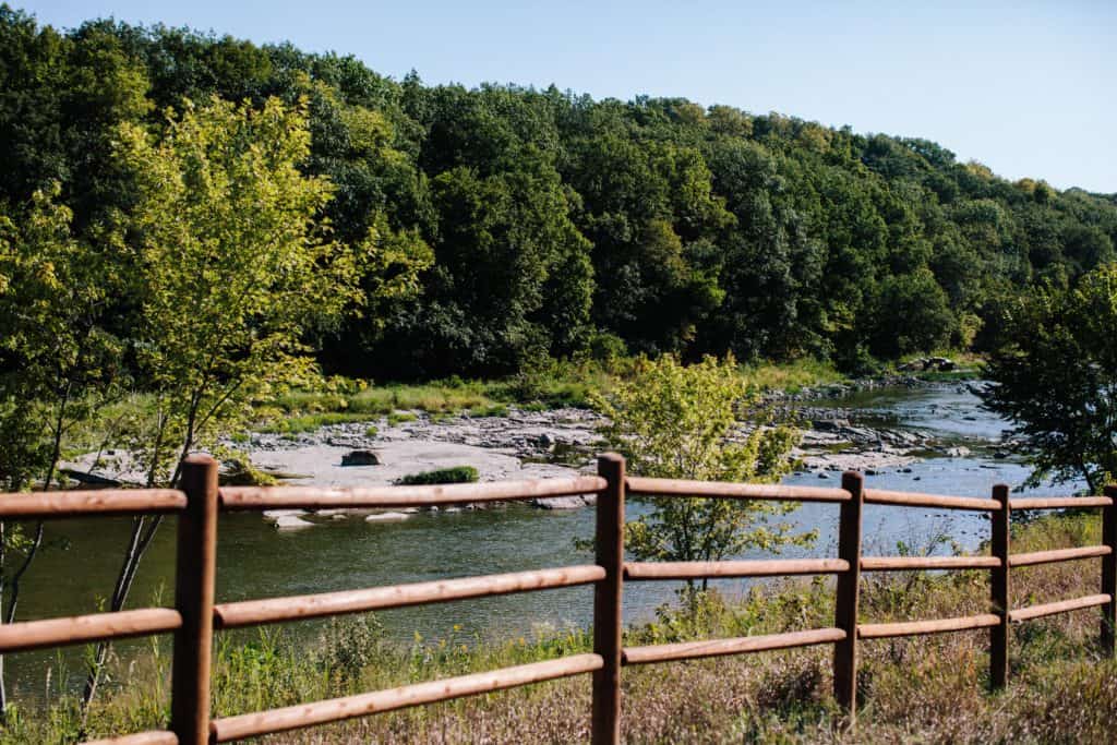 Camp Aramoni, a glamping site in Illinois, features a wooden fence next to a river.