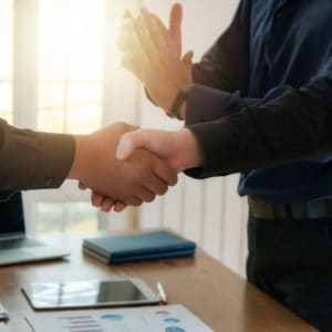 Two businessmen shaking hands at an office desk discussing the Palomino RV.