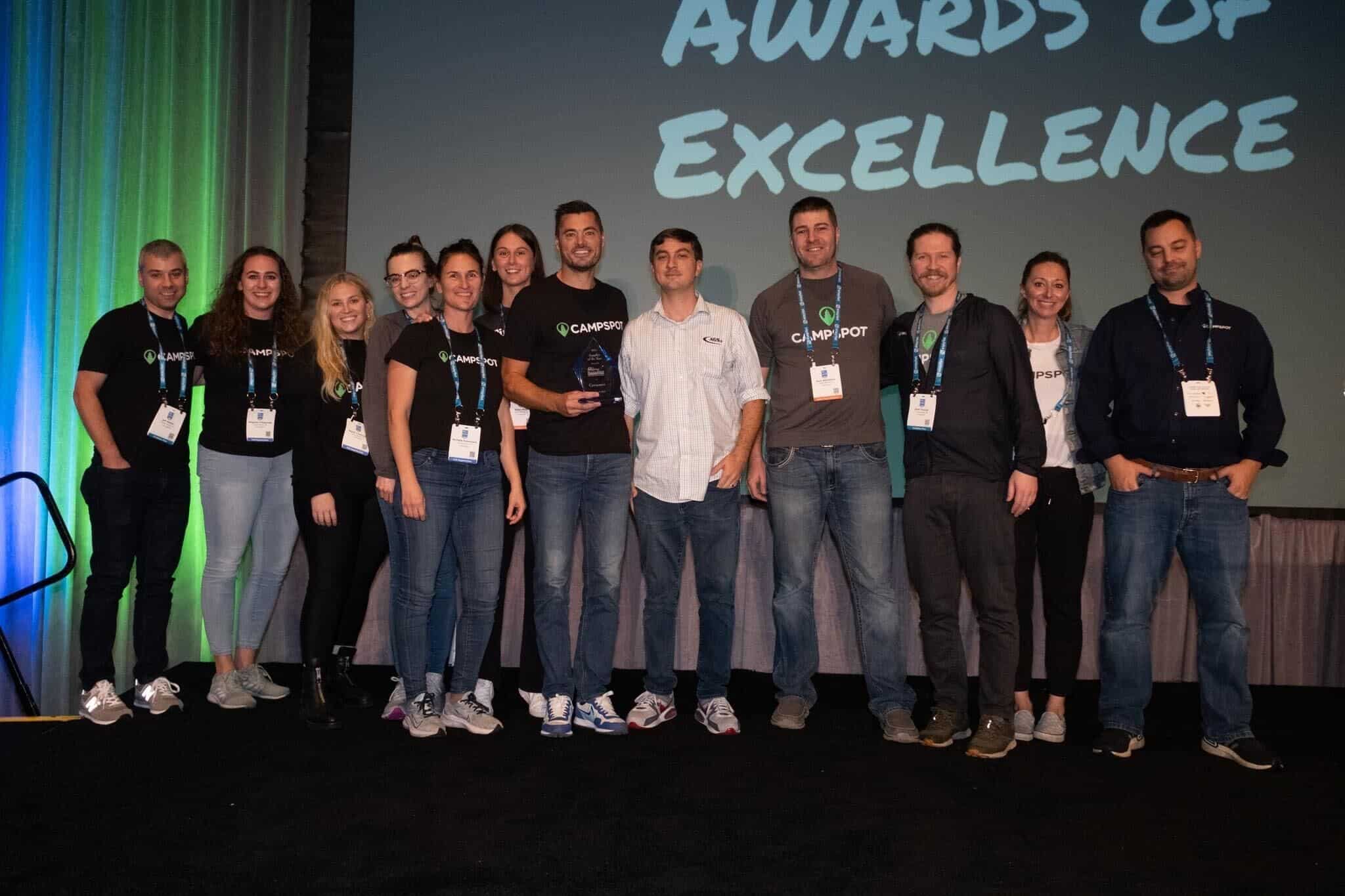 Campspot's CEO and an industry supplier standing in front of a screen that says awards of excellence, showcasing outdoor hospitality achievements.